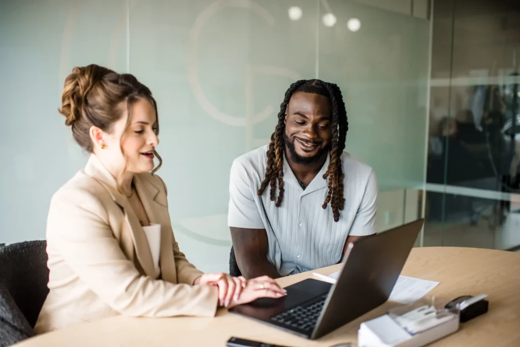 Advisor and a client smiling while reviewing information on a laptop at a conference table